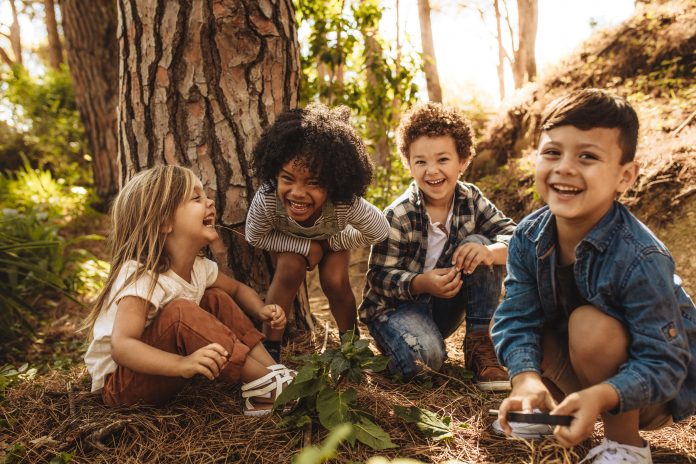 4 enfants riants au pied d'un arbre
