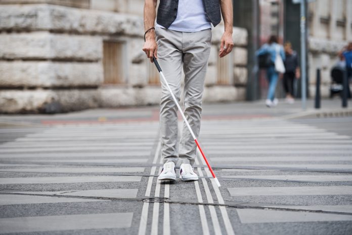 Aveugle avec canne blanche suivant une ligne