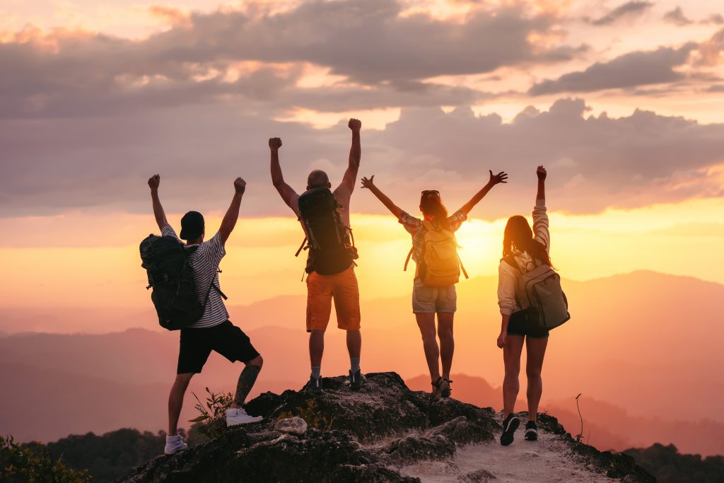 4 jeunes personnes au sommet d'une montagne victorieux