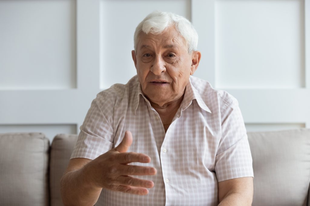 Vieil homme assis sur son canapé parlant