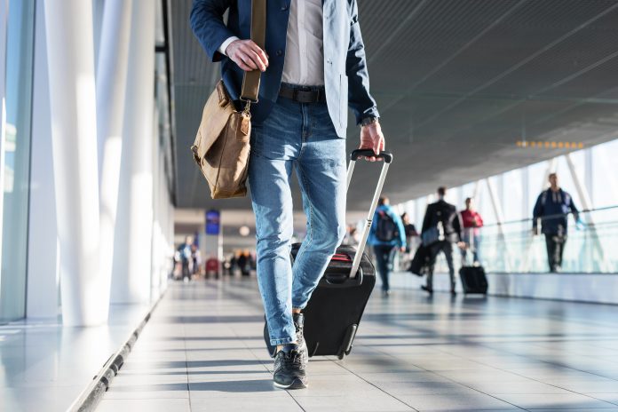 Homme en voyage dans un aéroport avec sa valise