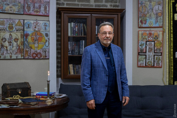 Sergueï Sarafaniouk, fondateur du musée de la franc-maçonnerie ukrainienne d'Odessa, devant les œuvres de Konstantin Skoptsov
